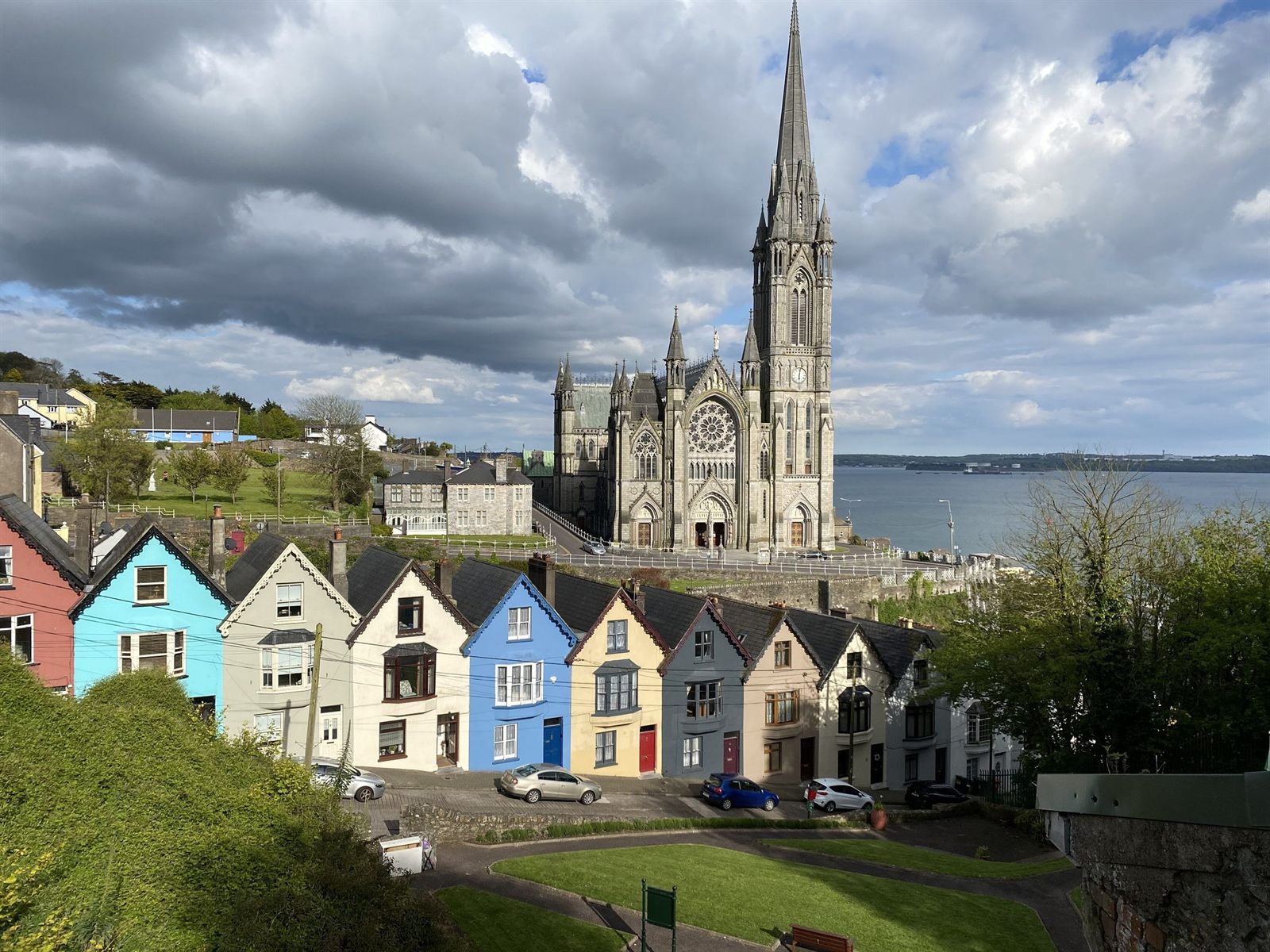 Row of brightly painted houses below a Gothic cathedral above Cork Harbour at Cobh