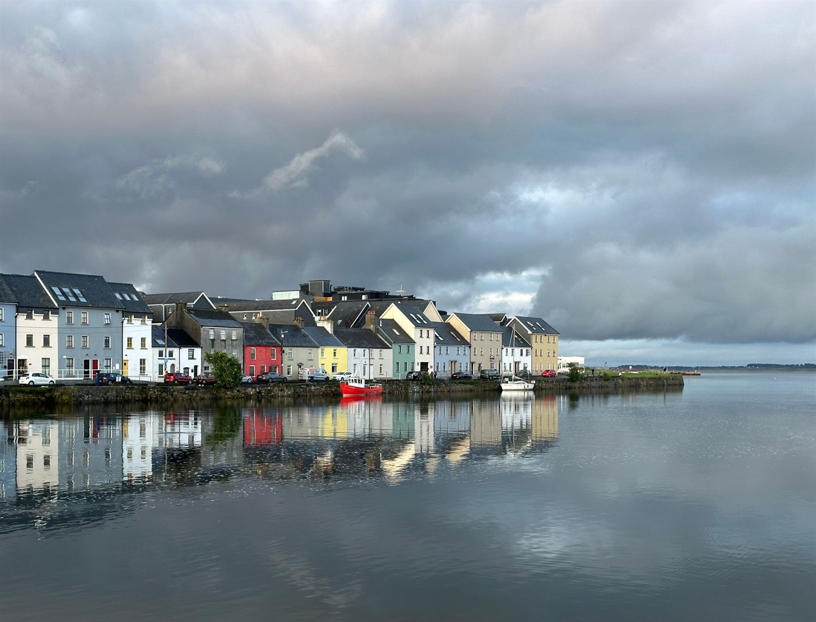 Colorful waterfront houses reflected in still water in Galway, Ireland